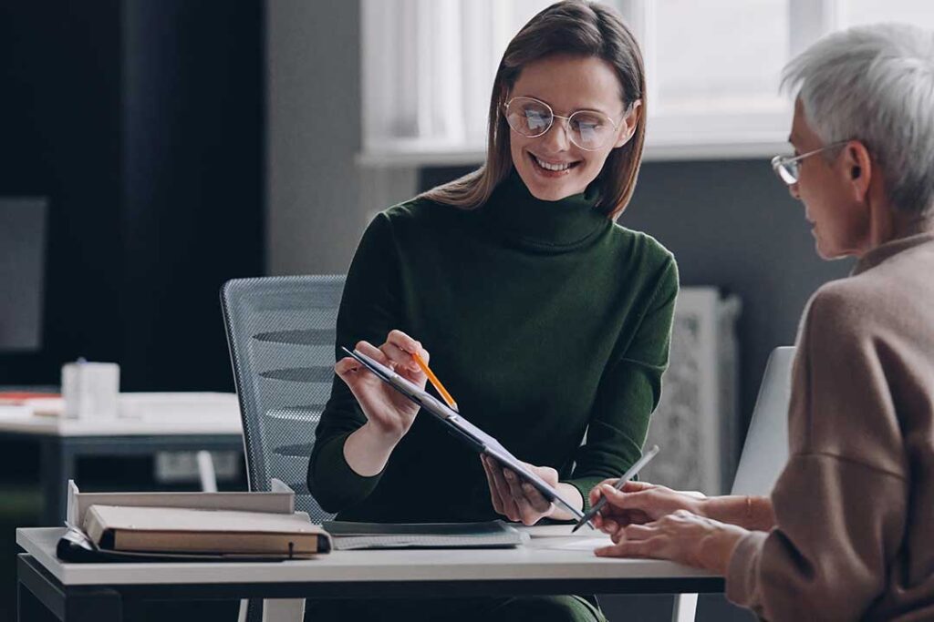 Person reviewing insurance papers beside a laptop, wallet, credit cards, and identity theft recovery documents.